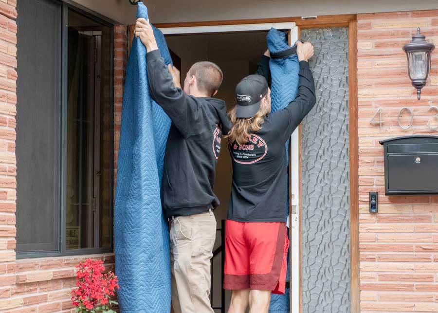 Movers protecting door trim with moving blankets